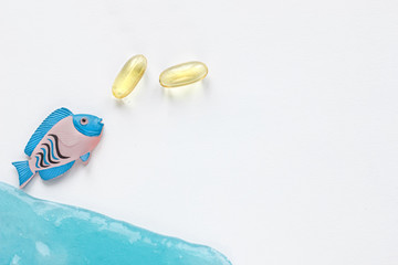 Fish collagen concept. Collagen capsules and fish on blue background. copyspace for text. Beauty and spa concept.