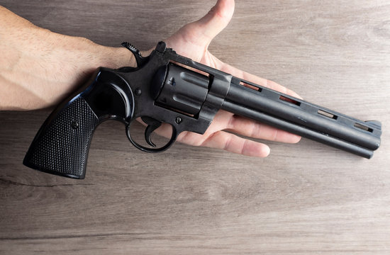 Mano de hombres con pistola rev&oacute;lver aislado sobre un fondo de madera