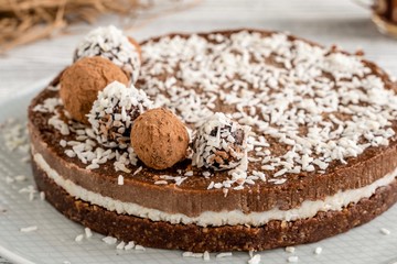  chocolate cake on a plate. Chocolate and coconut cake on a white wooden background. Foodfoto in a high key. Raw dessert