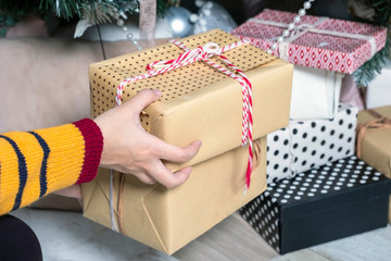 Close up of woman hands putting down a gift box under a Christmas tree.