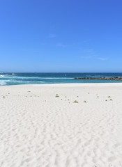 Summer landscape with white sand beach with rocks and waves on a sunny day. Galicia, Spain.