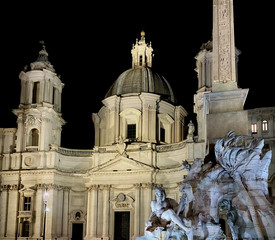 Obraz premium Night shot of the illuminated facade of the baroque church of Sant'Agnese in Agone with the fountain of the four rivers in Piazza Navona in Rome