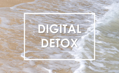 Digital detox text on sand with sea waves background.