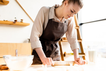 attractive woman rolling out dough with rolling pin
