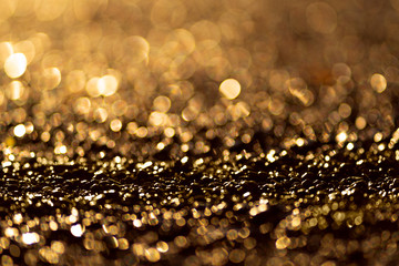 Sparkling light boke blur. Sea pebbles. Golden glitter particles background.