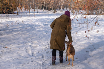 Young woman with dog walking in winter park.
