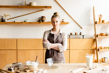 young woman standing with crossed arms near ingredients and easter bunnies figurines