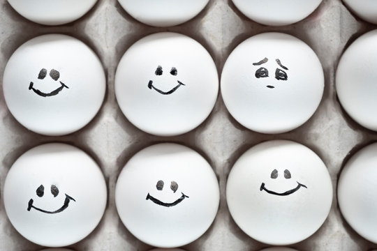 One egg with sad emotion among another eggs with happy emotions. Eggs with emotions.
