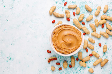 Homemade peanut butter with peanuts on grey concrete background,top view
