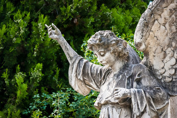 La statua di un angelo con il braccio alzato su una toma del cimitero monumentale di Bologna