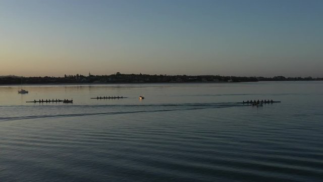 Scenic sunset aerial towards octuple rowing crews near Auckland, NZ
