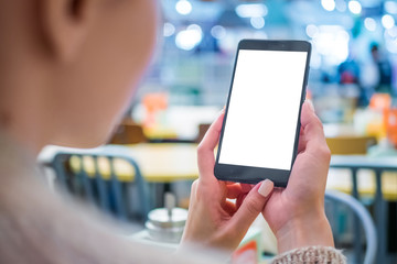 Mockup image: woman looking at black smartphone mobile device with blank white display at cafe, restaurant - close up view. Mock up, white screen, copyspace, template, isolated, technology concept