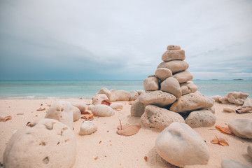Fototapeta na wymiar Folded pyramid Zen pebble stones on the sea beach at dramatic sky