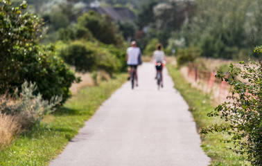Fototapeta na wymiar Kein Fokus, bewusst unscharf: Junges Paar fährt im Sommer mit Fahrrädern durch eine nordische Naturlandschaft, grafisches Element, extra ohne Fokus