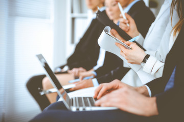 Business people working at meeting or conference, close-up of hands. Group of unknown businessmen and women in modern white office. Teamwork or coaching concept