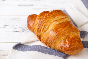 French rosy croissant on light napkin on white background. Bakery concept.