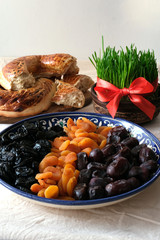 Traditional food of holiday Navruz: lavash bread, assortment of dry fruits. Young green wheat with red ribbon.