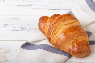 French rosy croissant on light napkin on white background. Bakery concept.