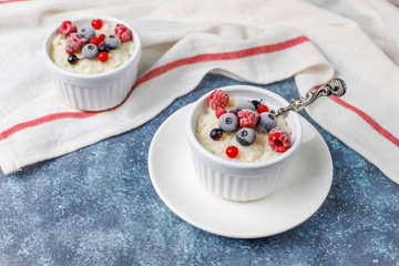 Rice pudding with frozen blueberries and raspberries in white bowl