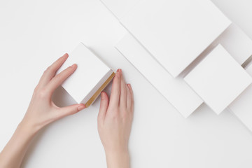 Mock up of white present box in women's hands on the white background surrounded with many different size white boxes