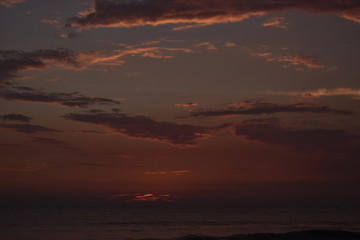 Fototapeta na wymiar Sunset in a ocean with a beautiful cloudy sky
