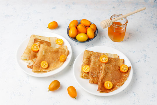 Delicious Breakfast on light background. Orthodox holiday Maslenitsa. Crepes with cumquats and honet,top view