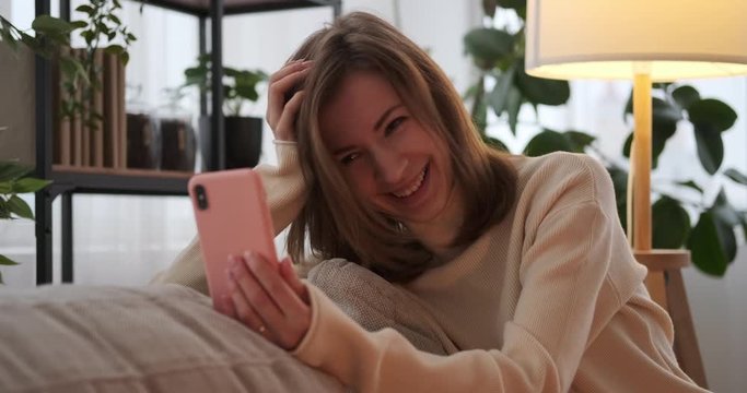 Woman laughing while talking on video call using mobile phone at home