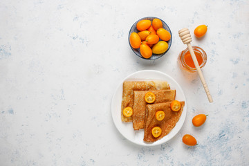 Delicious Breakfast on light background. Orthodox holiday Maslenitsa. Crepes with cumquats and honet,top view