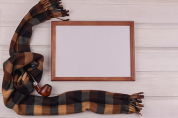 Composition for congratulations. Photo frame, scarf and smoking pipe on a white wooden background. View from above. Copy space. Father's Day, men.