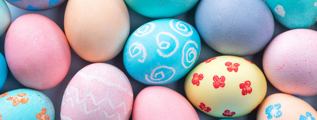 Colorful Easter eggs dyed by colored water with beautiful pattern on a pale blue background, design concept of holiday activity, top view, full frame.