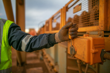 Inspector wearing a glove inspecting emergency stop safety device system on conveyor belt by pulling turning to the right will immediately stopping running heavy machinery prior system operation 