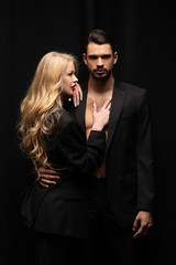 attractive curly woman touching handsome man isolated on black