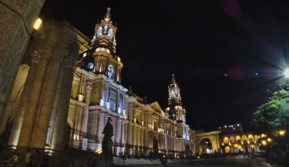 Fototapeta na wymiar Night photograph of the Basilica Cathedral of the city of Arequipa in southern Peru, the image shows the cathedral illuminated at night with people walking around