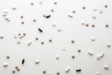 Scattered pills on a white wooden table. Pharmacy and pharmacology. Top view backgound. Pattern with pills.