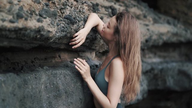 girl poses for camera leaning on cliff and adjusting hair