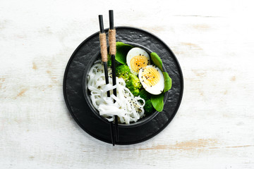 Rice noodles with egg, broccoli and spinach. Asian cuisine. Top view. Free space for your text.