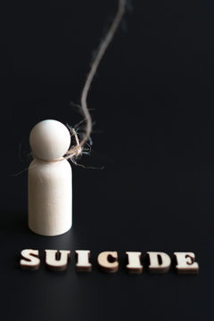 Suicide and depression concept. figurine of a man in a loop and the inscription suicide on a black background. vertical photo