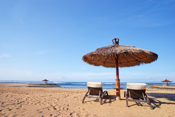 Vacation concept. Two sunloungers and umbrella on sand sea beach.