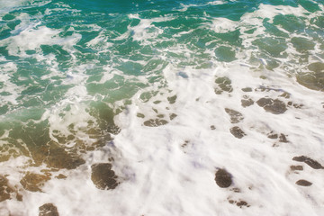 Top view texture waves, foaming and splashing in the ocean, sunny day.  Beautiful tropical sea in summer season image by aerial view. Abstract sea background. Ocean waves close-up.