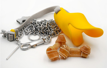 Yellow silicone muzzle with dog chain and knotted bone or rawhide on white background represent...