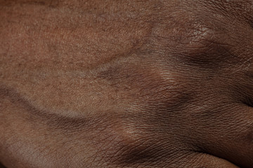 Fingers. Detailed texture of human skin. Close up shot of young african-american male body....