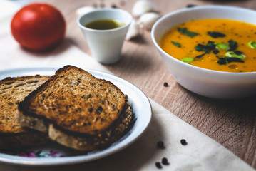 Pumpkin soup with toasted bread on table.
