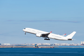 Fototapeta na wymiar 青空を背景に羽田空港を離陸する飛行機