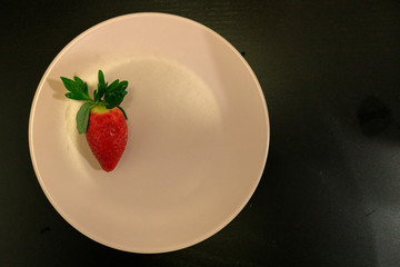 one strawberry on a plate