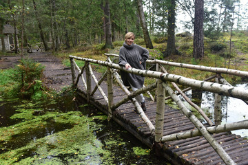 short-haired woman in gray on a wooden bridge