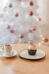 Italian coffee Cup and cupcake on the table near the Christmas tree with white bokeh