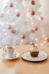 Italian coffee Cup and cupcake on the table near the Christmas tree with white bokeh
