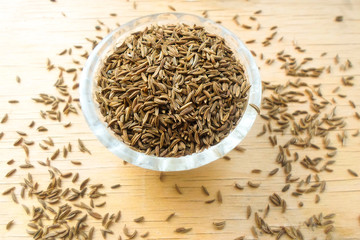 cumin in a glass cup on a wooden table