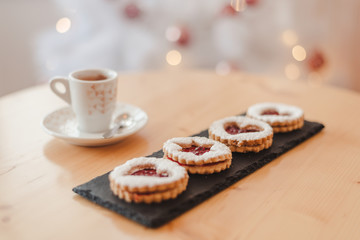 Italian coffee small Cup and cookie on the table near the Christmas tree with golden bokeh