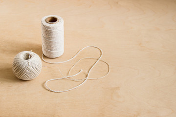 beige threads, twine on wooden background